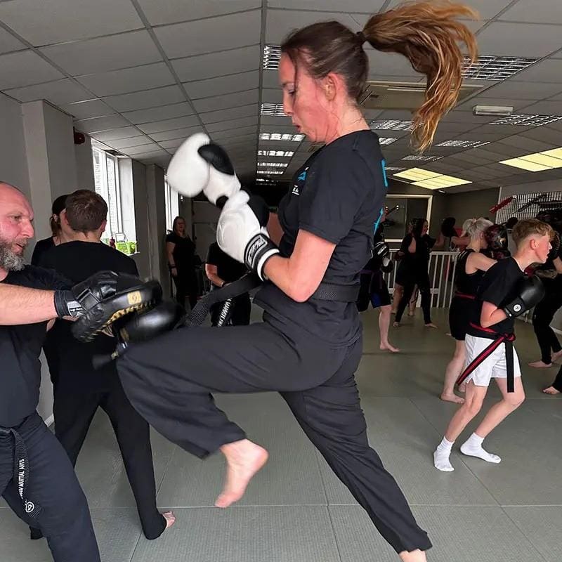 student doing a high kick for a martial arts lesson